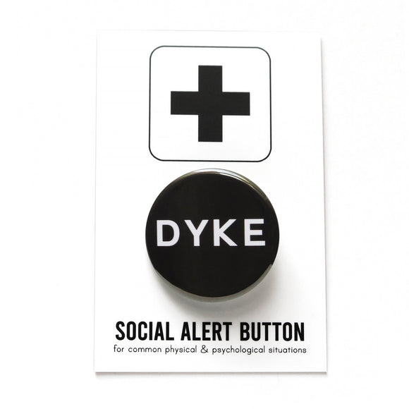 Round, black pinback button that reads DYKE in white text. Badge is on a Social Alert Button backing card.