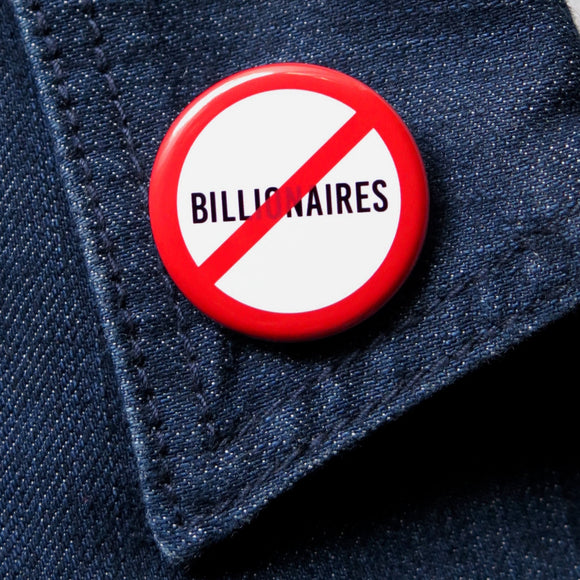 A round white button that reads NO BILLIONAIRES in black text with a red circle and slash to indicate being against billionaires. Badge is on dark blue denim jacket collar.