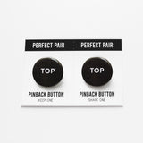 Two pinback buttons on a backing card with a center perforation to tear & share with a friend. Button the left reads TOP. Button on right reads TOP. Both buttons are black with white text.