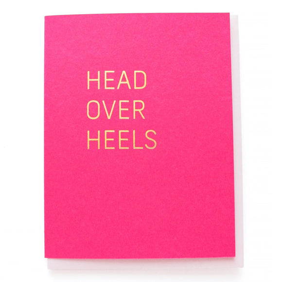 Magenta greeting card with gold, hot foil pressed text, that says HEAD OVER HEELS