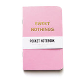 A small bubble gum pink pocket notebook with rounded corners, gold embossed text reading SWEET NOTHINGS, with a white belly band that reads Pocket Notebook.