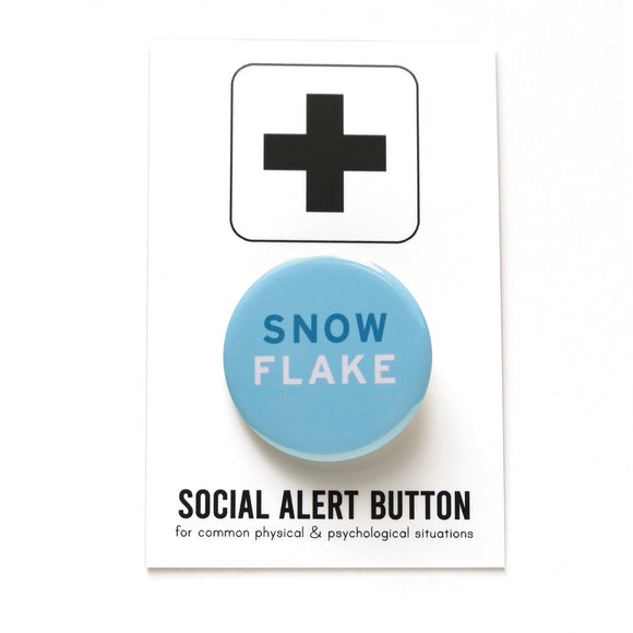 Light blue round pinback button that reads SNOW in medium blue  and FLAKE  in white serif text.  Button is on a Social Alert Button backing card.