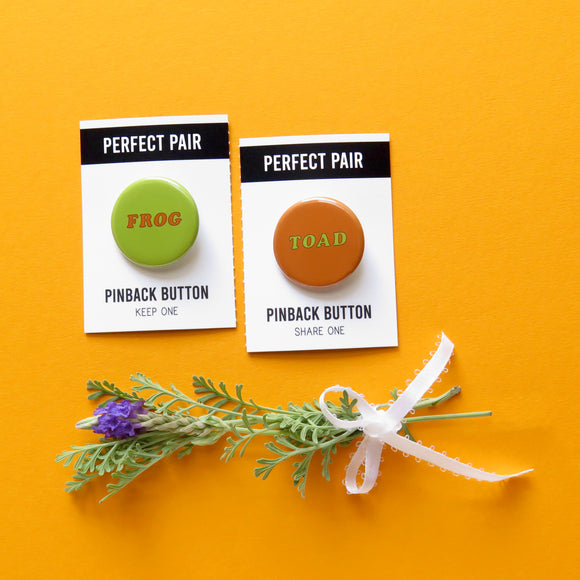 Two pinback buttons side by side.  A green button that says 