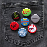 A bunch of round colorful anti-genocide pinback buttons pinned to a black denim pocket, phrases include: Free Palestine, Grieving, End The Genocide in Gaza, Dont Stop Talking About Palestine, Ceasefire!, Arms Embargo Now! & No Apathy.