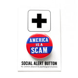A round red pinback button with blue rectangles to pop white text that reads AMERICA IS A SCAM. Button is on a Social Alert Button backing card.