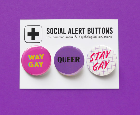 Three round pinback buttons on a Social Alert Buttons backing card. Buttons left to right: A dark Pink button that reads WAY GAY in yellow text, A purple button that reads QUEER in black text, and a 1980's style lavender grid button that reads STAY GAY in pink script.