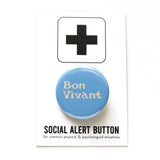 Round, light blue pinback button with cream text that reads BON VIVANT on two lines. Pinned to a Social Alert Button backing card.