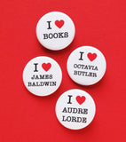 Four round white buttons on a red background, reading I Love Books, I love James Baldwin, I love Audre Lorde, I love Octavia Butler.