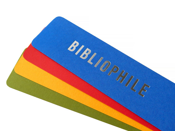 Four bright colored bookmarks fanned out, the top one is a bright blue bookmark that reads BIBLIOPHILE in silver embossed text.And there is an orange-red, marigold yellow and deep moss green bookmarks fanned below, with no visible text.