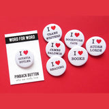 Seven round white I heart pinback buttons on a red background. Reading, I LOVE - Trans Writers, James Baldwin, Reading, Books, Bookstore Cats, Audre Lorde & Octavia Butler.