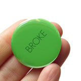 Round pinback button that says BROKE. Dark green text on a kelly green background.