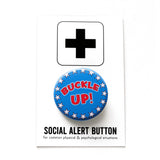 A round blue pinback button with an outline of white stars, that reads BUCKLE UP in red text in the m middle