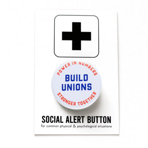 Around white button that reads BUILD UNIONS in bold text in the center. The upper curve reads: Power in Numbers, in orange text, The lower curve reads, Stronger Together in orange text. Button is pinned to an orange denim pocket.