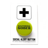 Round yellow green pinback button that says CALIFORNIA SOBER in dark green text. Button is pinned to a Social Alert Button backing card