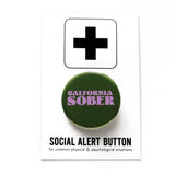 Round dark green pinback button that says CALIFORNIA SOBER in lavender text. Button is pinned to a Social Alert Button backing card.