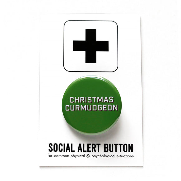 Round, dark green pinback button that says CHRISTMAS CURMUDGEON in white text with a black shadow. Button is on a Social Alert Button backing card.