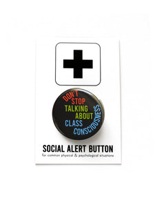 A round black pinback button with lime green. rust read and blue  text that reads SDONT STOP TALKING ABOUT CLASS CONSCIOUSNESS. The Button is held in a hand.
