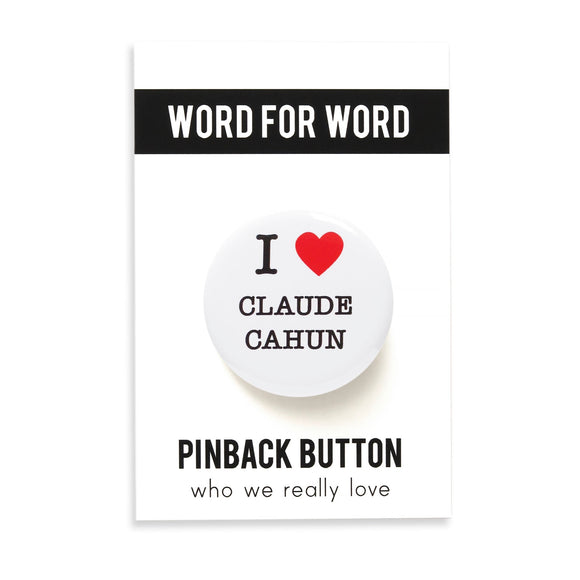 A round white pinback button that reads I LOVE CLAUDE CAHUN with love being a red heart. Button is pinned to a WORD FOR WORD Branded Backing Cards, What We Really Love