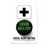 Round black pinback button with green text that reads COVID KILLJOY. Button is on a Social Alert Button backing card.