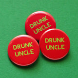 Three round red 1.25" holiday pinback button that reads DRUNK UNCLE in light green text. Buttons are on a green background.