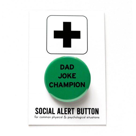 Round pinback button that says DAD JOKE CHAMP. Black text on a green background. Button is on a SOCIAL ALERT BUTTON backing card.