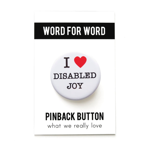 A round white pinback button that reads I LOVE DISABLED JOY in a black serif font, the love being indicated by a red heart. Badge is on a Word For Word branded backing card that reads Pinback Button, What We Really Love.