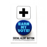 Blue round pinback button that reads EARN MY VOTE! in chunkylight blue text. Button is on a Social Alert Button backing card.