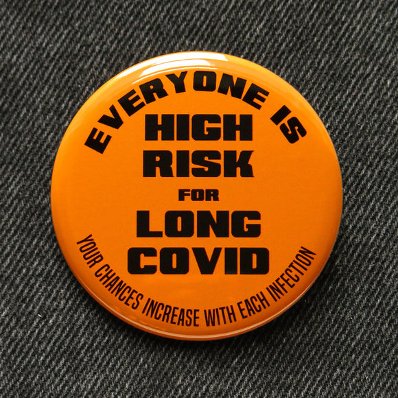 Round bright orange pinback button that reads Everyone Is High Risk For Long Covid, Your chances increase with each infection. Button is pinned to black denim