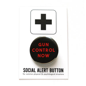 Round black pinback button that reads GUN CONTROL NOW in red text on three lines. Badge is on a Social Alert Button backing card.