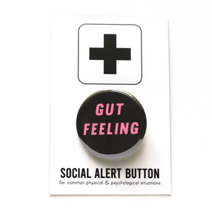 Round black pinback button with pink text reading GUT FEELING on two lines. Badge is on a Social Alert Button backing card.