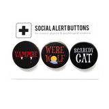 Three round pinback buttons lined up on a SOCIAL ALERT BUTTONS backing card. Reading left to right: VAMPIRE in black & red, WERE WOLF in brown & black, and SCARDEY CAT in black & white.