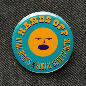 A round teal pinback button that reads HANDS OFF Civil Rights & Social Safety Nets yellow-orange text,  with an angry shouting face in the center of the button. 