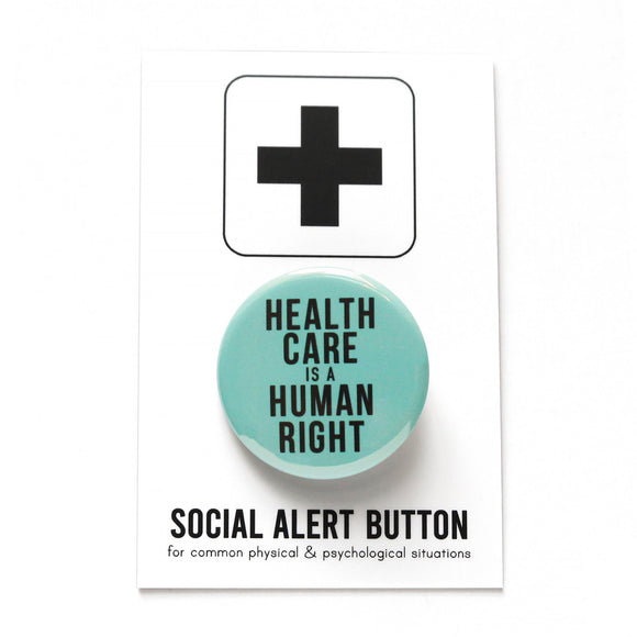 Round pinback button that says HEALTHCARE IS A HUMAN RIGHT. Black text on a hospital blue-green background. Button is on a SOCIAL ALERT BUTTON backing card