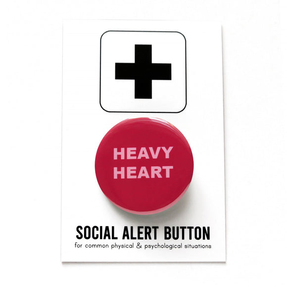 Round dark pink magenta pinback button that reads HEAVY HEART on two lines in a chunky light pink font. Badge is on a Social Alert Button backing card.