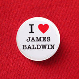 Round white button that reads I red heart James Baldwin. Button is pinned to a red sweatshirt