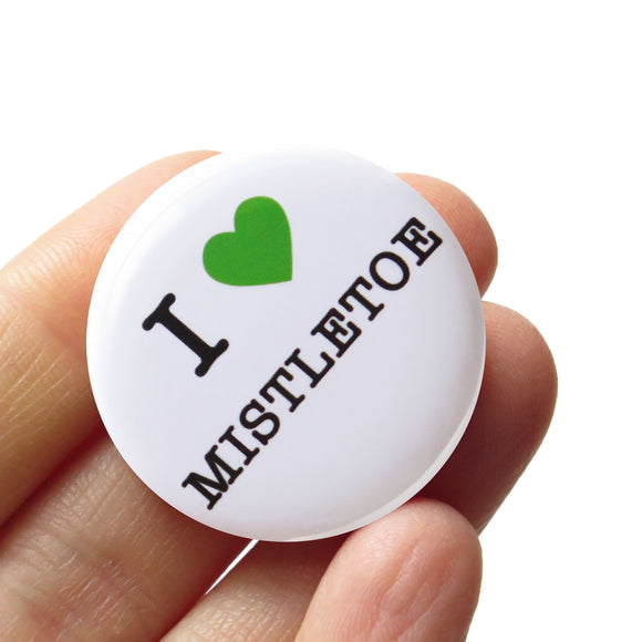 Round, white pinback button that says I LOVE MISTLETOE in classic black text with 
