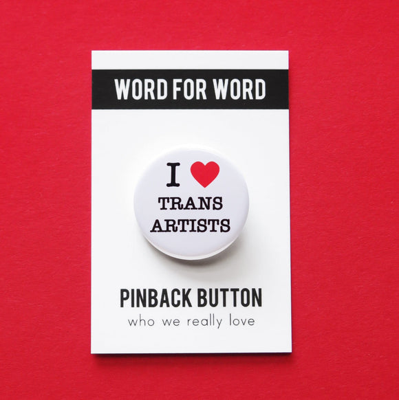 Round white pinback button with a bright read heart that reads I HEART TRANS ARTISTS in classic black type. Button is on a white backing card, with a black band at the top with WORD FOR WORD in white text. Below reads: PINBACK BUTTON, Who We Really Love.