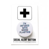 Round white pinback button that reads I'M INFUSED WITH MICROPLASTICS in a hollow font filled with tiny colored dots. Button is on a Social Alert Button backing card.