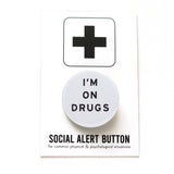 Round, white pinback button that reads I'M ON DRUGS in black san serif text. Badge is on a Social Alert Button backing card.