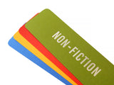 Four bright colored bookmarks fanned out, the top one is a moss green bookmark that reads NON-FICTION in silver embossed text. And there is an orange-red, marigold yellow and blue bookmarks fanned below, with no visible text.