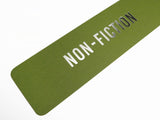Close up of rich mossy green vertical bookmark that reads NON-FICITON in gunmetal silver foil embossed text.