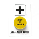 Round pinback button that says OUT OF ORDER. Black text on a yellow background. The button is pinned to a Social Alert Button backing card.