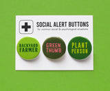 Three round pinback buttons in different shades of green, lined up on a SOCIAL ALERT BUTTONS backing card. Reading left to right: Backyard Farmer, Green Thumb, Plant Person.