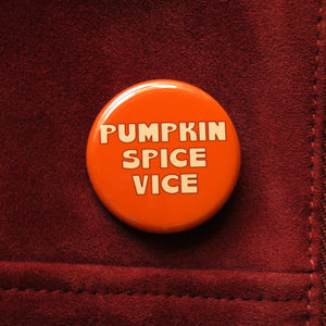 Round orange pinback button that reads Pumpkin Spice Vice in a cinnamon creme text.  Button pinned to redwood suede  leather jacket.