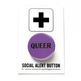 Round purple pinback button that reads QUEER in black text. Pinned to a Social Alert Button backing card,