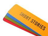 Four bright colored bookmarks fanned out, the top one is a marigold yellow bookmark that reads SHORT STORIES in silver embossed text. And there is an bright blue, moss green & red-orange bookmarks fanned below, with no visible text.