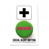 Round rich green pinback button reads SICKO! in hot pink text. On a white backing card, black plus sign at the top. Below reads: Social Alert Button, with tiny text beneath it which says, for common physical & psychological situations