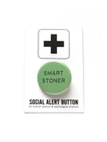 Round pinback button that says SMART STONER. Dark green text on a light green background. Button is pinned to a social alert button backing card.