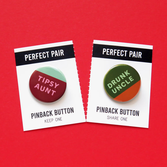 Two round pinback buttons: left is wine red, pink & mint green and reads TIPSY AUNT. Right button is dark green background, mint green text that reads DRUNK UNCLE and a little half moon of whisky orange-brown at the bottom, to look like a partially drunk cup of whiskey. These buttons are on a perforated backing card that tears down the middle. Each Half reds PERFECT PAIR, Pinback Button, left side reads KEEP ONE. Right side reads SHARE ONE.