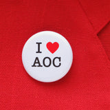 I heart AOC pinback button on the lapel of a red blazer